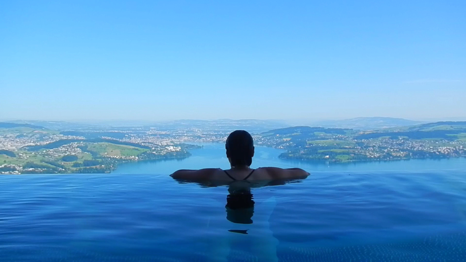 Blick aus dem Infinity-Pool über den See – Startbild des Bannervideos «Exklusive Lagen und unvergessliche Momente»