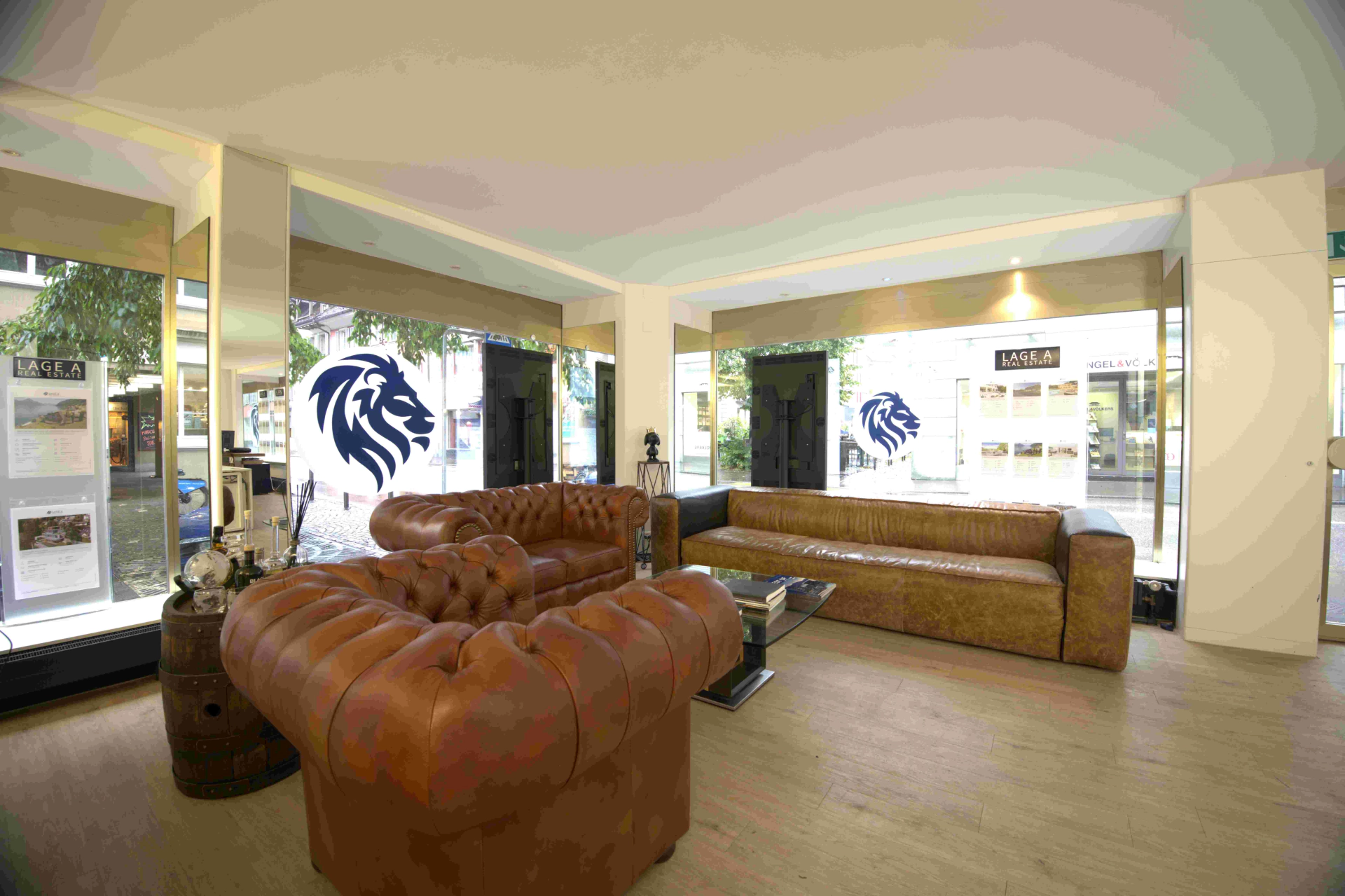 Empfangsbereich im Büro von LAGE A Immobilien in Zug mit Ledersofas und Lion-Signet an den Fenstern